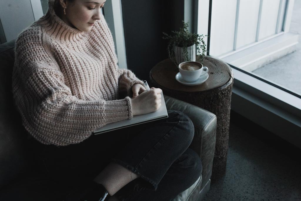 Woman in a sweater practicing how to journal effectively